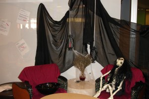 Skeleton in one chair, empty chair for user to sit next to. Decorated for Halloween